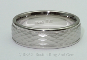 Men's platinum wedding ring with diamond shaped pattern and mill grain edge details.