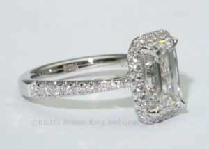 Emerald cut diamond set in a fishtail set tapered cathedral halo.