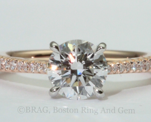 Round brilliant cut diamond set in a two tone solitaire engagement ring. 18k rose gold tapered cathedral band with French cut set diamonds with looped four prong platinum basket