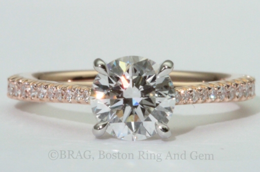 Round brilliant cut diamond set in a two tone solitaire engagement ring. 18k rose gold tapered cathedral band with French cut set diamonds with looped four prong platinum basket