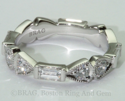 Platinum and diamond eternity wedding ring. Emerald and round brilliant cut diamonds set in triangular and rectangular alternating shapes with mill grain details